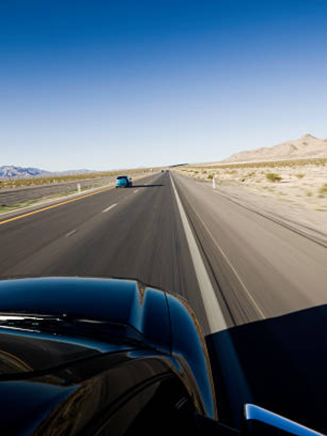  A vintage car driving down a deserted highway, the landscape blurring past the open window.