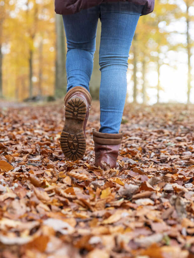  A woman walking through fall leaves, wearing comfortable and stylish boots.
