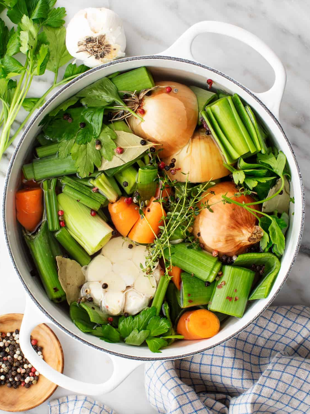 A person happily cooking in a kitchen filled with fresh vegetables.
