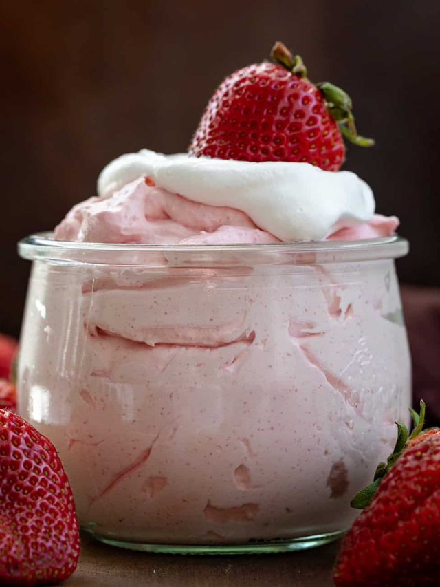 A bowl of fresh berries with a dollop of whipped cream on top.
