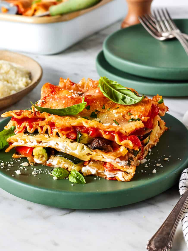 A close-up of a cheesy vegetarian lasagna with layers of pasta, vegetables, and melted cheese.
