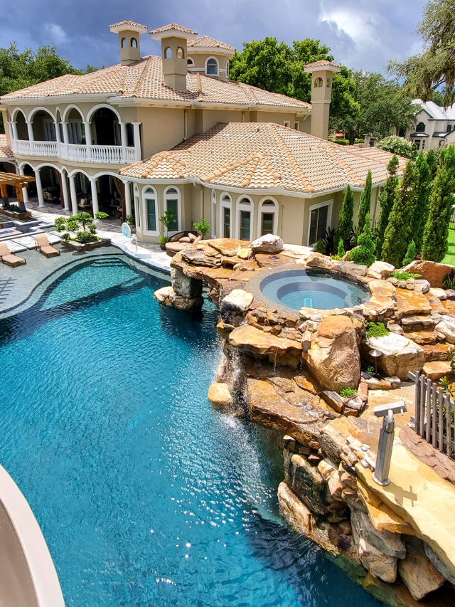 Cascading water crashing down a moss-covered rock face into a crystal-clear pool surrounded by lush greenery.
