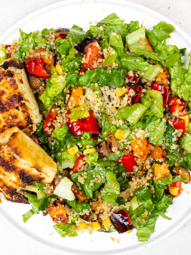 A sheet pan filled with roasted vegetables, tofu cubes, and quinoa.
