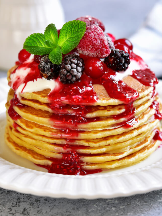  A stack of fluffy pancakes with fresh fruit and whipped cream.
