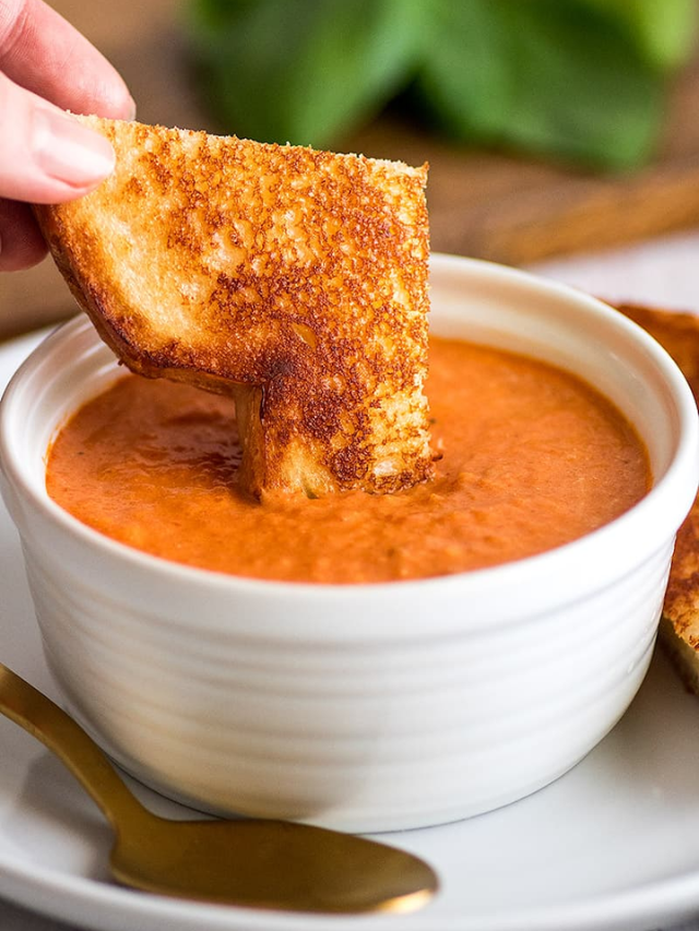A bowl of tomato soup with a grilled cheese sandwich

