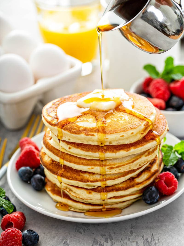 A plate of pancakes with eggs and fruit
