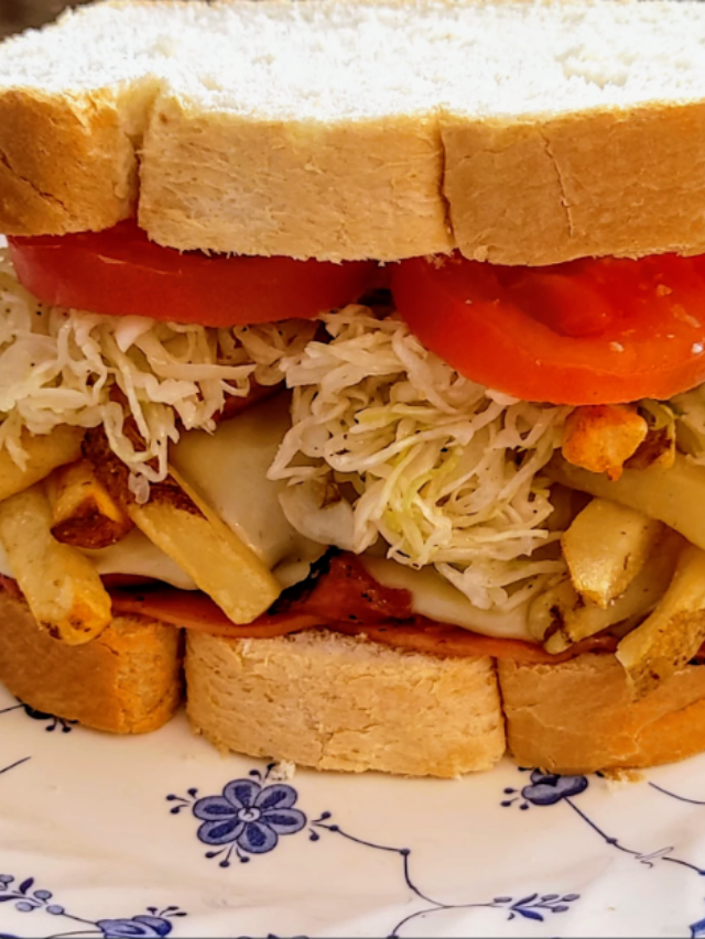 A mouthwatering close-up of a Pittsburgh-style Primanti Bros. sandwich with french fries overflowing from the sides.
