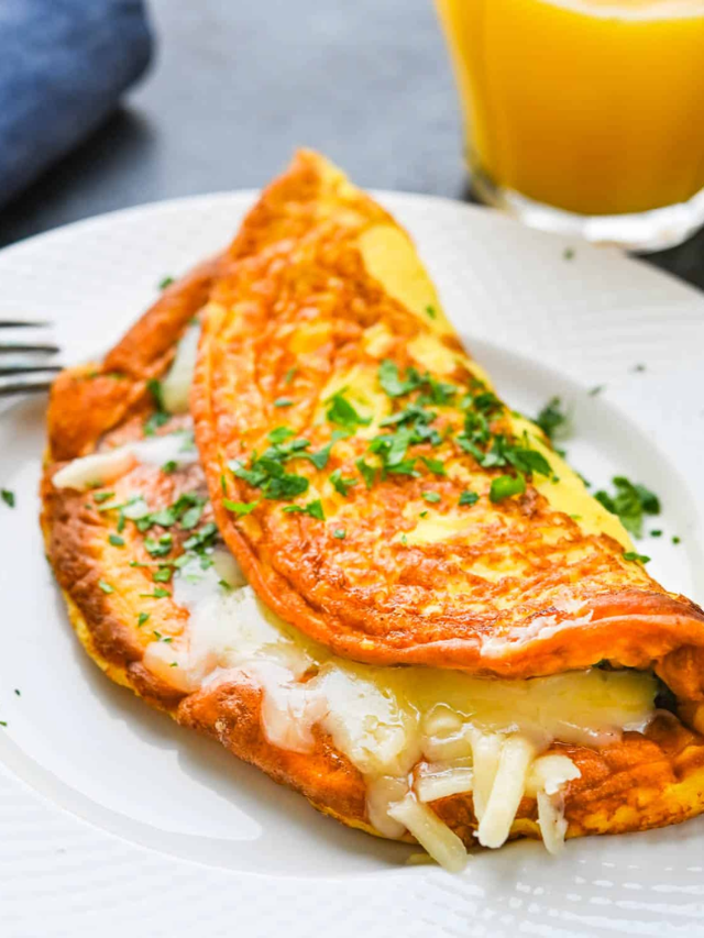 A fluffy omelette filled with spinach, mushrooms, and cheese, served on a plate.
