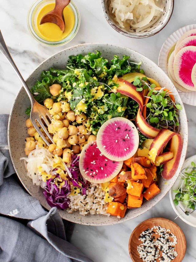 A colorful bowl filled with brown rice, roasted vegetables, chickpeas, and a tahini dressing