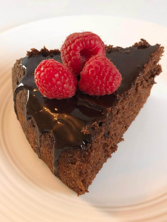 A slice of rich chocolate avocado cake with a raspberry on top.
