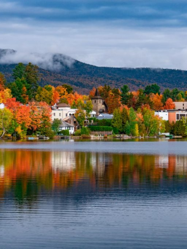 A serene image of a kayak gliding across a lake surrounded by colorful fall foliage.
