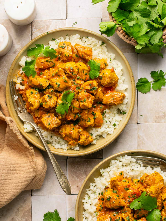 A photo of a crock pot filled with chicken tikka masala, with a side of rice and naan bread.
