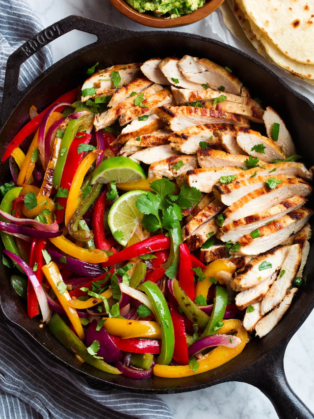 A colorful sheet pan fajita dinner with bell peppers, onions, chicken, and black beans.
