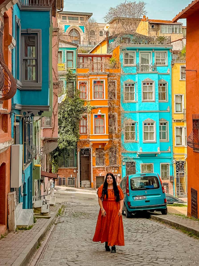 Vibrant street scene with historic brick buildings, outdoor cafes, and people strolling.
