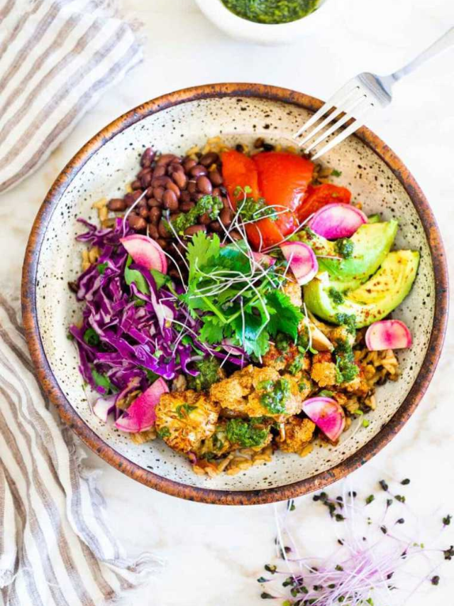 A Buddha bowl with quinoa, roasted chickpeas, avocado, kimchi, and a creamy tahini dressing.
