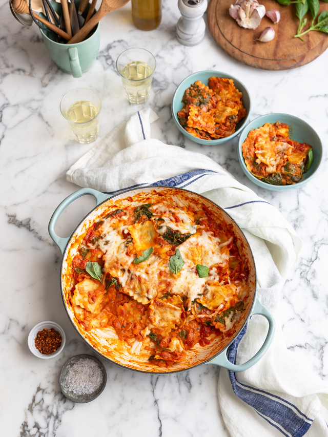 A large pot with creamy tomato pasta with chicken and spinach.
