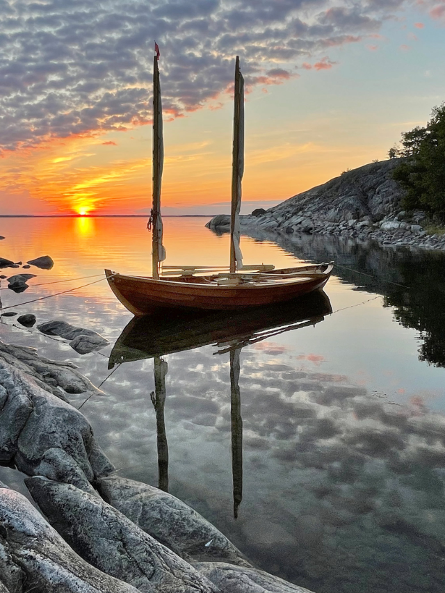 Picturesque scene of a long pier jutting out into the ocean, with sailboats dotting the horizon.
