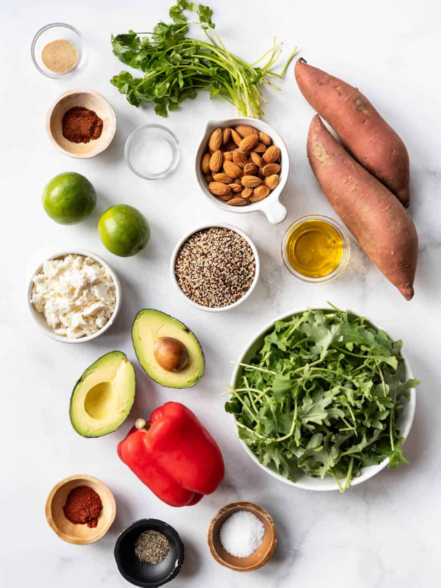 A buddha bowl filled with quinoa, roasted vegetables, chickpeas, avocado, and a tahini dressing.
