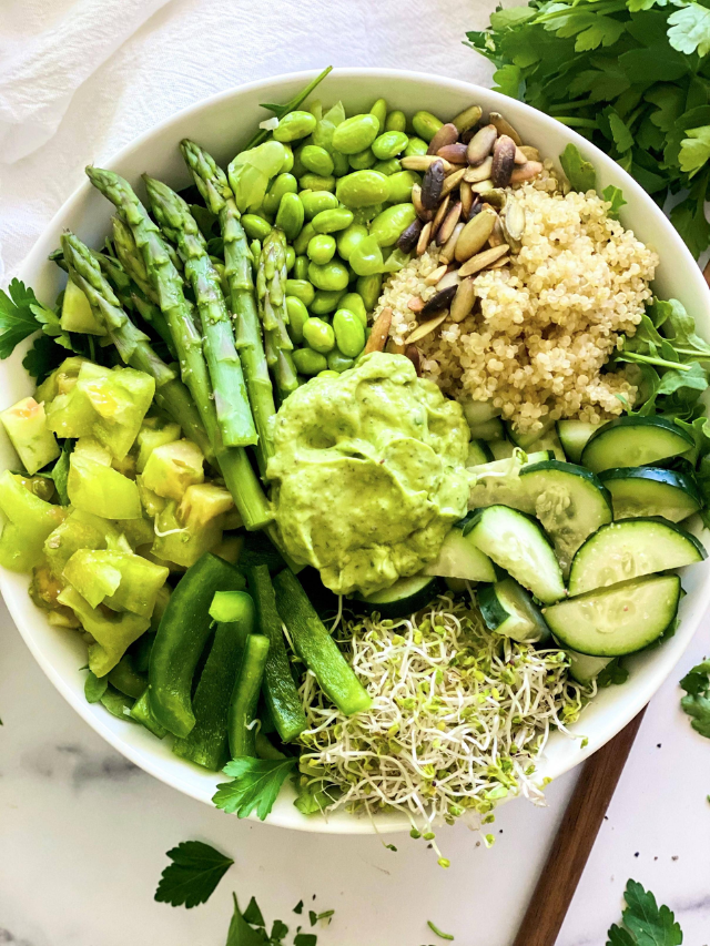 A Buddha bowl filled with colorful vegetables, tofu, and a tahini dressing.
