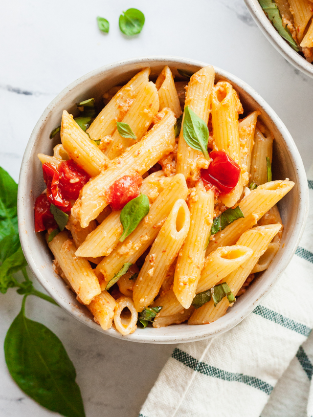  A plate of one-pan pasta with cherry tomatoes, spinach, and feta cheese.


