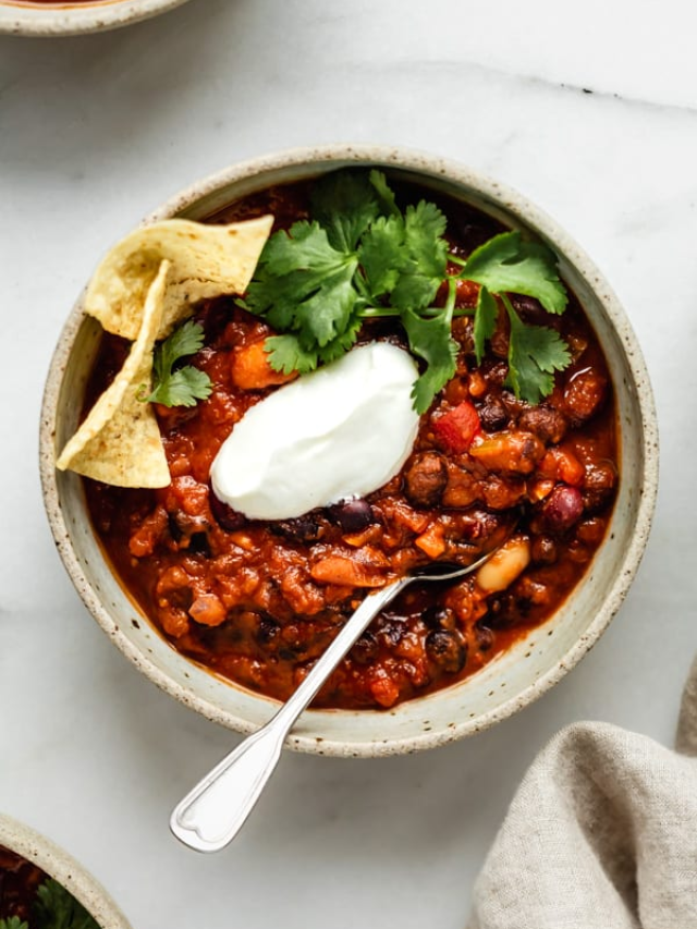 A steaming bowl of chili topped with shredded cheese and sour cream.
