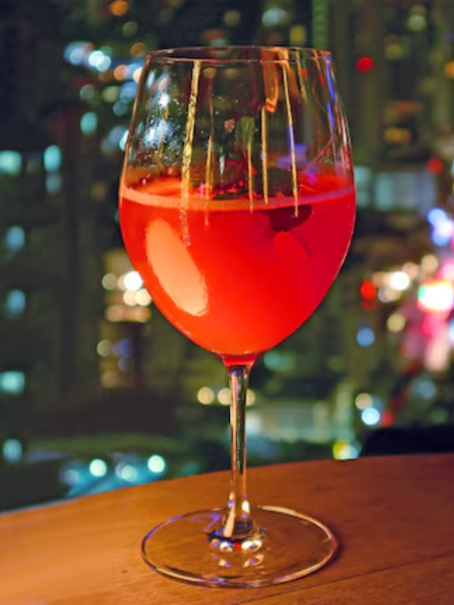 A bustling nightlife scene showcasing people enjoying drinks on a rooftop bar with city lights in the background.
