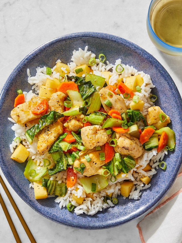 A colorful chicken stir-fry with vegetables and rice.
