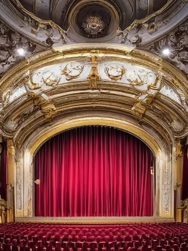 The interior of a historic theater with ornate decorations and a stage set for a performance.
