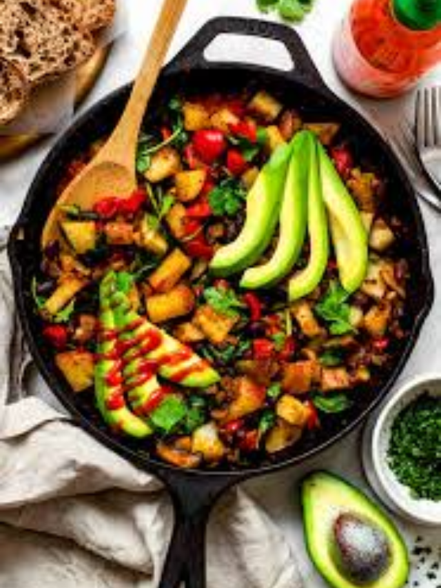 A cast-iron skillet filled with a breakfast hash with ground beef, potatoes, onions, and peppers.
