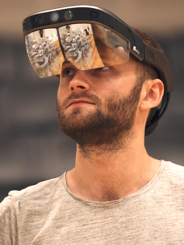  A person looking frustrated while holding a pair of AR glasses and a phone.
